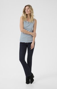 Striped tank top in blue and white with scalloped hem, paired with dark wash flared jeans and black heeled ankle boots. Simple design elements.