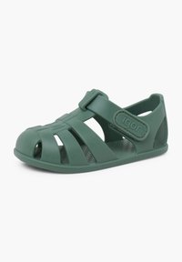 Sandalia de goma verde con punta abierta, diseño recortado y correa ajustable. Cuenta con una suela interior texturizada y un logo en la correa.