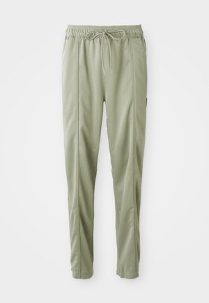 Pantalon de survêtement vert clair effilé avec taille élastique et cordon, avec des détails de coutures verticales le long des jambes.