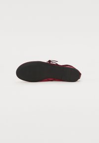 Scarpa rossa con tomaia in rete, design con lacci e suola in gomma nera. Presenta un motivo testurizzato sulla tomaia e una silhouette slanciata.