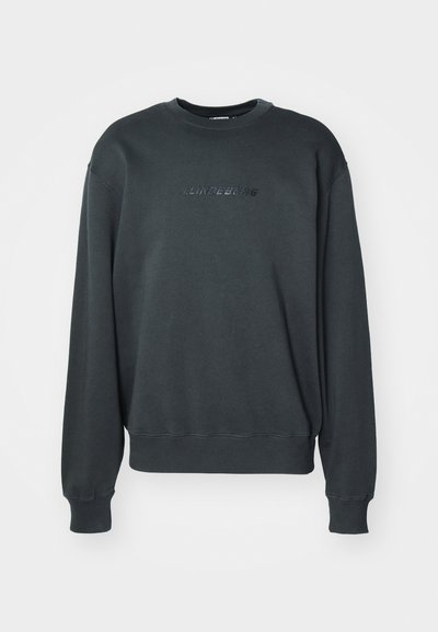 Σκούρο γκρι φούτερ με στρογγυλή λαιμόκοψη, μακριά μανίκια, ριγέ μανσέτες και μια διακριτική λογότυπο στο στήθος. Κατασκευασμένο από μαλακό ύφασμα.