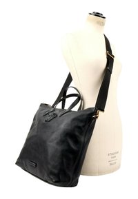Sac à bandoulière en cuir noir avec double poignée présenté sur un mannequin blanc de forme robe sur fond blanc.