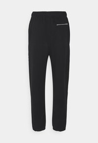 Pantalones negros de tela suave con cintura elástica, que cuentan con un bolsillo con cremallera y tobillos ajustados para un diseño entallado.