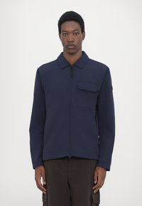 Navy blue, lightweight jacket with a subtle texture, a front zipper, and a chest pocket. Features a classic collar and long sleeves.