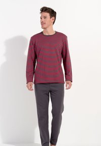Långärmad skjorta med röda och marinblå horisontella ränder, rundad halsringning, ihop med grå slim-fit byxor. Slät textur och avslappnad design.