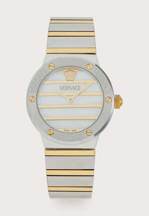 Montre Versace avec un boîtier rond en argent, des bandes d'accent dorées, un cadran blanc rayé et des détails de logo ; bracelet en acier inoxydable avec des bandes dorées alternées.