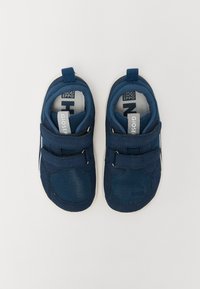 Sapatilhas desportivas azul marinho com materiais em malha e camurça, apresentando duas tiras de Velcro ajustáveis e uma sola de borracha branca.