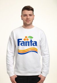 Bílá mikina s modrým logem "Fanta" s oranžovými tečkami a zelenými dotaženými detaily, doplněná žlutými a modrými vlnkovými vzory.