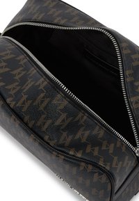 Bolso tote de patrón negro y marrón fabricado en material sintético con cremalleras plateadas y un interior espacioso, que presenta una textura suave.