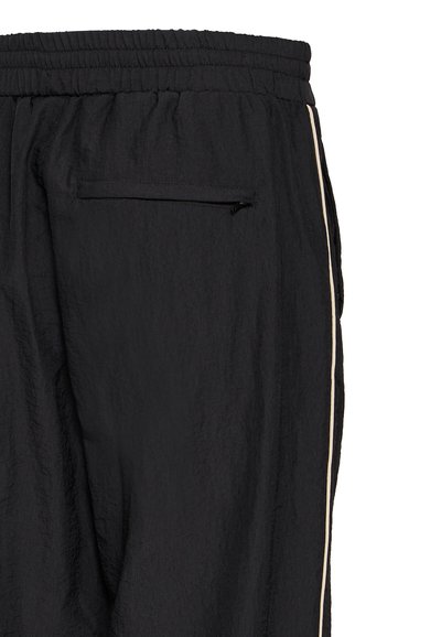 Schwarze Jogginghose mit strukturiertem Finish, schlanker Schnitt, weißen Seitenstreifen und einem mit Reißverschluss versehenen Gesäßtasche.