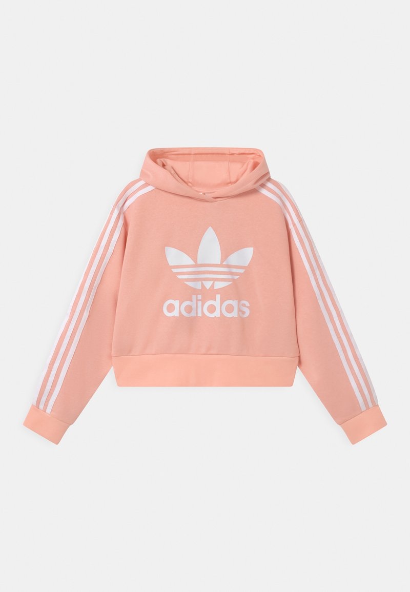 Světle růžová zkrácená mikina s kapucí, s bílým logo adidas, bílými třemi pruhy na rukávech a přední klokaní kapsou. Měkká textilie.