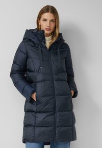 Manteau matelassé bleu marine avec capuche, doté d'une fermeture éclair frontale, de cordons de serrage ajustables et de poches latérales. Design texturé avec un motif matelassé.