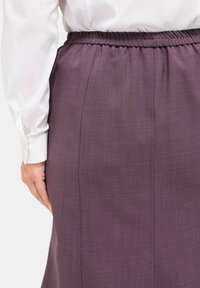 Lila, knielanger Rock mit glatter Textur, elastischem Bund und dezenten Nahtdetails. Rückansicht mit schlichter Gestaltung.