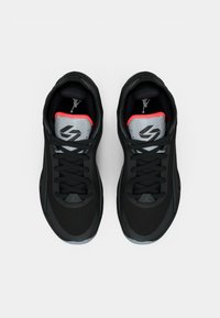 Μαύρα αθλητικά παπούτσια με άνω μέρος από δίχτυ, κόκκινες λεπτομέρειες και γκρι στοιχεία. Διαθέτουν εμφανές σύστημα κορδονιών και λογότυπο στη γλώσσα. Εξωτερική σόλα από καουτσούκ.