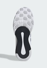 Podeszwa białego buta sportowego z czarnym owalnym wzorem gripu w centrum oraz teksturowanymi kwadratami w obszarze palców i pięty.