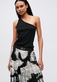 Μαύρη ραμμένη μπλούζα με έναν ώμο, συνδυασμένη με φούστα πλισέ σε μαύρο και άσπρο σχέδιο που διαθέτει μαύρη ζώνη με το λογότυπο 'Karl'.