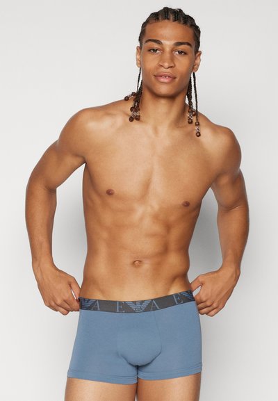Bóxers de algodón azules con una cinturilla de logo en contraste, diseño ajustado, textura suave y detalles cosidos. Sin decoración adicional.
