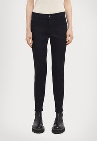 Black denim skinny jeans with a mid-rise waist, five-pocket design, and a smooth texture. Features metallic button hardware.