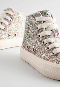 Høje sneakers med hvide snørebånd og såler, dækket af multicolor glimmer med stjernemønstre på en neutral baggrund.