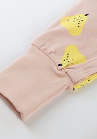 Light pink fabric sleeve with yellow pear patterns and small dark spots. Features a ribbed cuff and a snap button detailing at the end.