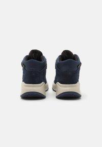 Námořnické vysoké boty s svrchním dílem ze semiše, béžovou podrážkou a černým lemováním; obsahují boční zip pro snadný přístup.