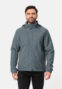 Giacca impermeabile grigia con chiusura a zip, cappuccio regolabile e polsini elasticizzati. Realizzata in un materiale leggero e liscio, adatto per l'abbigliamento outdoor.