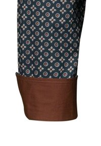 Tessuto con motivo a fiori blu, marrone e bianco. Finitura marrone ai polsini, texture liscia e vestibilità sartoriale.