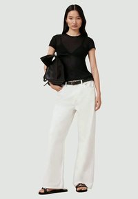 Top negru, ajustat, cu mâneci scurte, asortat cu pantaloni albi, lejeri, curea neagră și rucsac negru. Se poartă sandale cu talpă joasă.