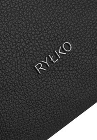 Cuir noir texturé avec une finition à grain subtil, présentant un logo en relief argenté "RYŁKO" positionné en diagonale.