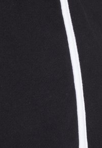Tecido preto com uma textura suave, apresentando uma faixa branca vertical de destaque. O design é simples e monocromático.