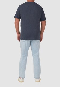 Marineblauses T-Shirt mit kurzen Ärmeln aus strukturiertem Stoff, kombiniert mit hellblauen Jeans, die einen lockeren Schnitt und normale Taschen aufweisen.