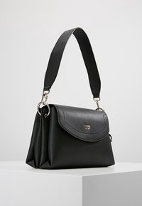 Mustat nahkalaukut, joissa on rakenteellinen muotoilu, sileä pinta, läppä sulkija ja irrotettava hihna. Hopeiset metalliosat.