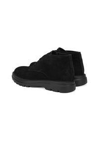 Schwarze Wildleder-Stiefeletten mit strukturierter Oberfläche, runder Zehenpartie und dicker schwarzer Gummisohle. Minimalistisches Design ohne sichtbare Beschläge.