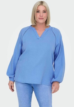 Helles Blau, langärmlige Bluse, lockere Passform, V-Ausschnitt, texturiertem Stoff, detaillierte Nähte an den Schultern, kombiniert mit hellblauen Jeans.