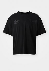 Tricou negru cu mânecă scurtă, din bumbac, având un guler rotund ajustat, grafica subtilă pe față și un design relaxat al tivului.