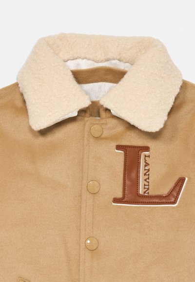 Smeđi kaput od vune s kremasto bež kragnom od ovčje kože, zlatnim dugmadi i smešnim kožnim 'L' logom. Glatka tekstura s detaljnim akcentima.