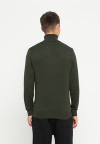 Pulover tricotat de culoare verde închis, cu guler înalt, mâneci lungi și un design strâmt. Textură netedă cu manșete și tiv cu dungi.