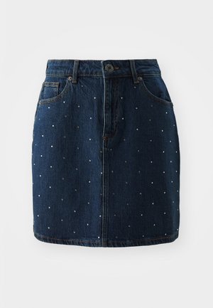 La falda de mezclilla presenta un tono azul oscuro con adornos de tachuelas plateadas distribuidos uniformemente por la tela, cierre de botón y bolsillos clásicos.