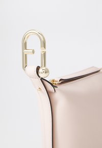 Bolso de cuero rosa con un cierre de metal dorado, textura suave, ribetes en negro que contrastan y forma redondeada.