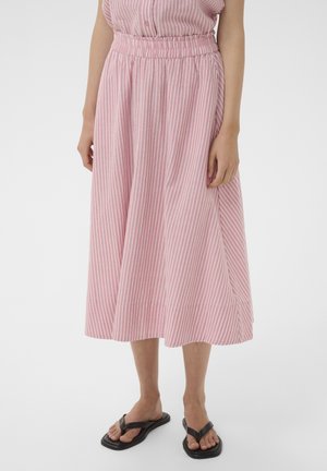 Vrouw draagt een roze-witte midi rok met verticale strepen, een elastische tailleband en zwarte teenslippers, staand op een witte achtergrond.