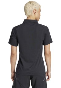 Polo shirt nero a maniche corte con colletto, texture liscia e dettagli di design minimi, dotato di una spalla posteriore e accenti di cucitura.