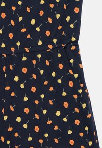 Marinblått tyg prytt med ett spritt blommönster i orange, gult och vitt, med gröna stjälkar; mjuk bomullstextur.