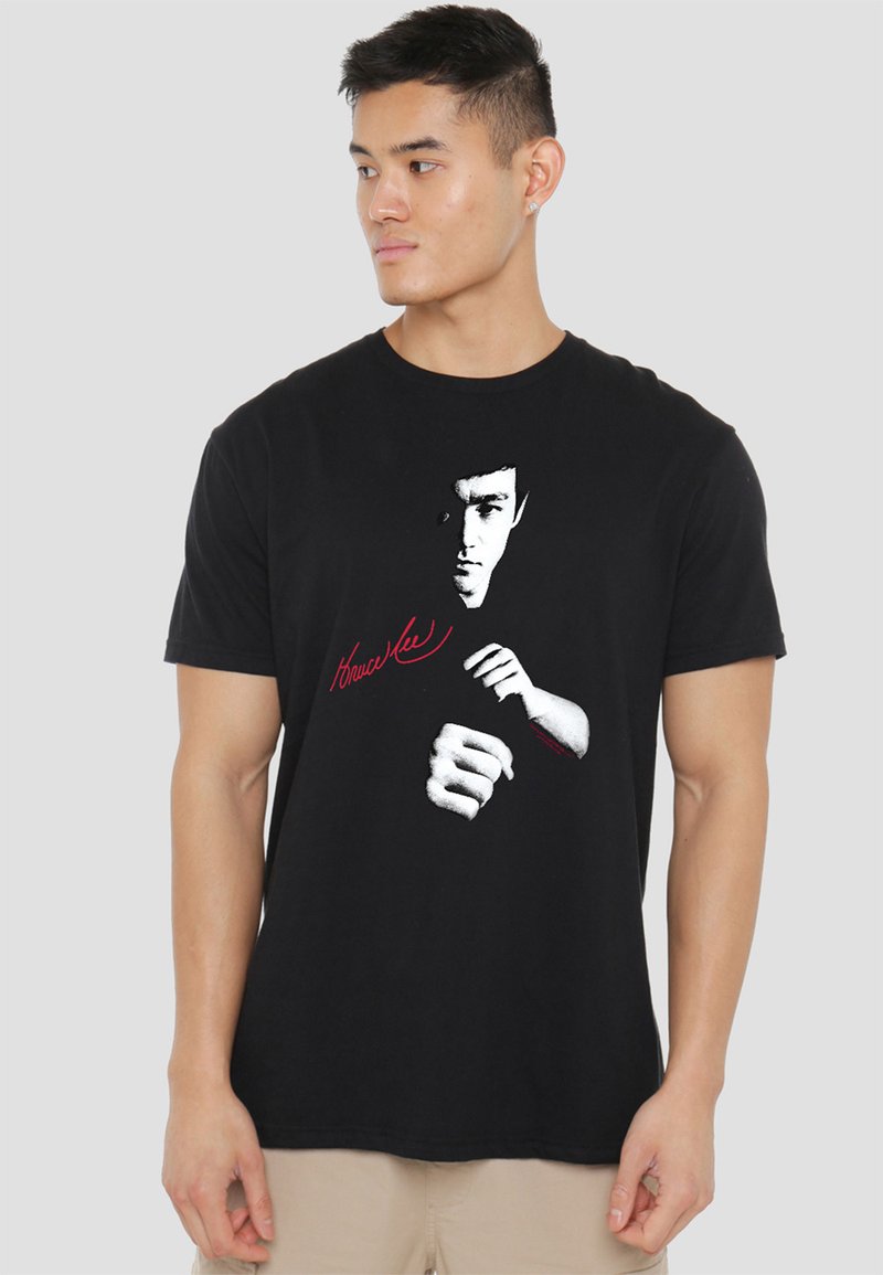 Black cotton t-shirt featuring a graphic of Bruce Lee's face and fists in white, with "Bruce Lee" text in red underneath the image.