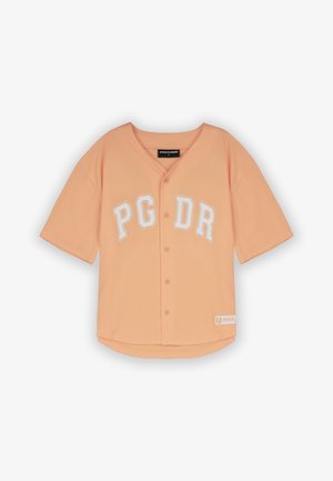 Perzikkleurig shirt met korte mouwen en een knoopsluiting aan de voorkant, met witte opschrift "PG DR." Het heeft een ronde zoom en een geribde halslijn.