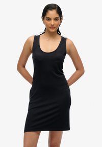 Robe noire à dos nu en tissu extensible, silhouette ajustée, décolleté arrondi, design sans manches et longueur au genou.