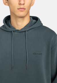 Dark teal hoodie made of cotton blend fabric, featuring a front pocket, adjustable drawstrings, and embossed logo on the chest.