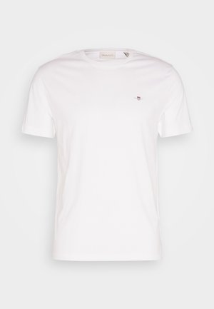 T-shirt en coton blanc avec un col rond, des manches courtes et un petit logo brodé sur la poitrine. Texture douce, design simple.
