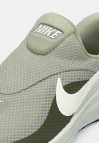 Ανοιχτό πράσινο sneaker Nike slip-on με υφή στην επάνω επιφάνεια, λευκό λογότυπο και κυρτές σχεδιαστικές λεπτομέρειες στο πλάι και στη σόλα.