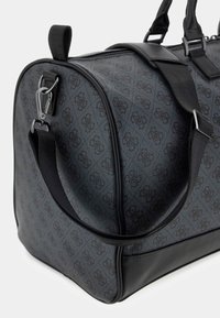 Borsa da viaggio nera con motivo, realizzata in tessuto testurizzato, con dettagli in pelle, manici robusti e una tracolla rimovibile. Dotata di chiusura a zip e accessori in metallo.