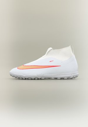Chaussure de football blanche avec virgule Nike rouge, semelle texturée et design sans lacets sur fond clair uni.